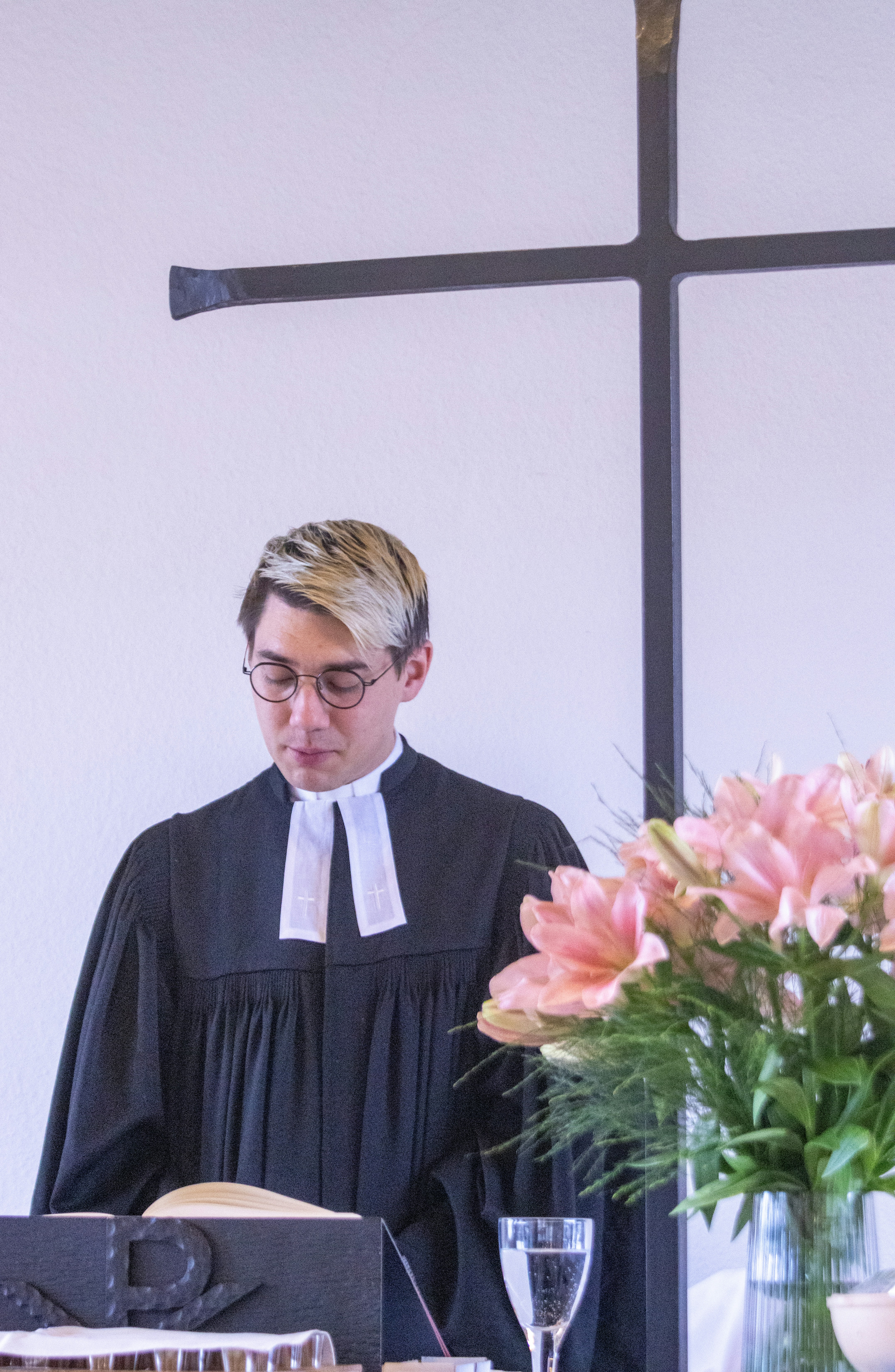 A man standing in front of a cross in a room